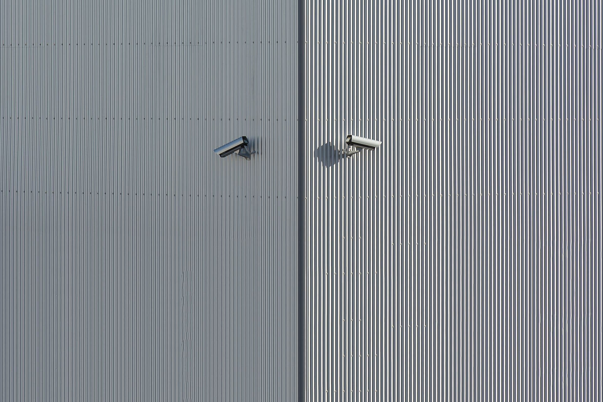 Two security cameras mounted on a corrugated metal warehouse wall